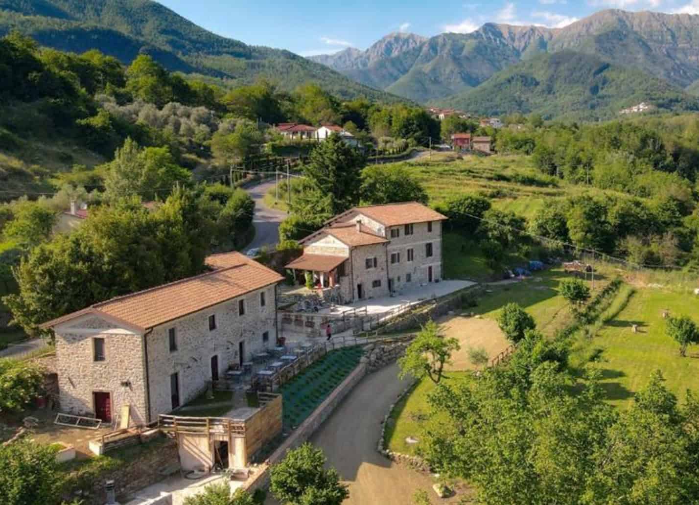 Aerial view of La Cascina Dei Chicchi Stone Buildings and Pastures framed by Appenino Mountains.